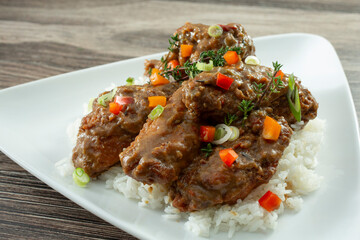 A closeup view of a plate of smothered fried chicken wings.