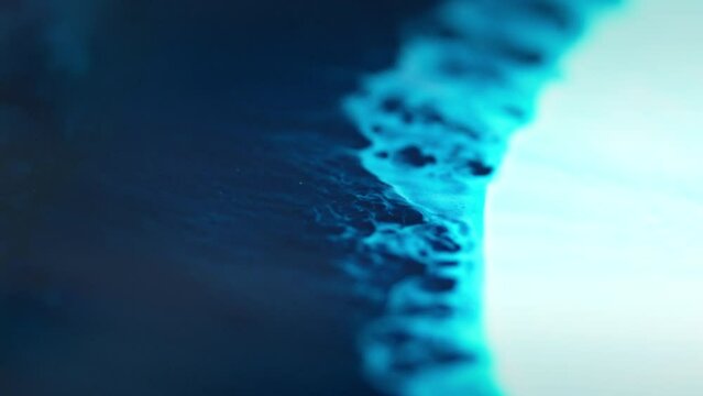 Close-up of blue ink diffusing in water, creating an abstract, swirling effect