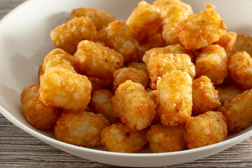 A closeup view of a bowl of deep fried tater tots.