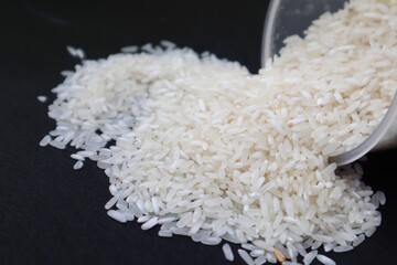 Rice fell from its place and some scattered around it on a black background.