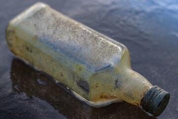 Close up shot of Decomposed Glass bottle at the beach. Ocean Pollution concept.