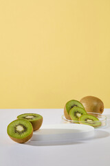 Concept of healthy skin with slices and halves of kiwi displayed with a podium on yellow background. Vacant space on the podium to show product of Kiwi fruit extract