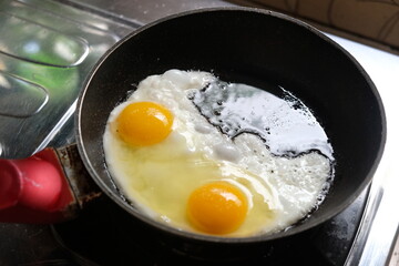 sunny side up eggs on a black frying pan on a gas stove. telur ceplok or mata sapi.