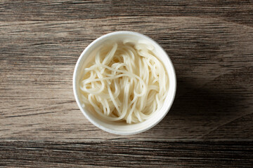 A top down view of a cup of cooked rice noodles.