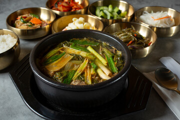 A view of a bowl of short rib soup, among several banchan bowls.