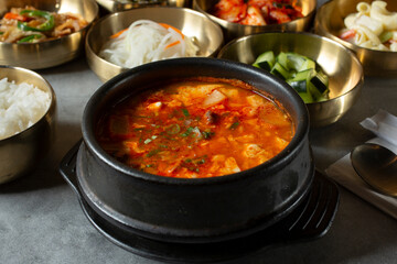 A view of a bowl of soon tofu soup, among several banchan bowls.
