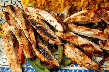 A top down view of a sliced chicken breast, part of a plate of fajitas.