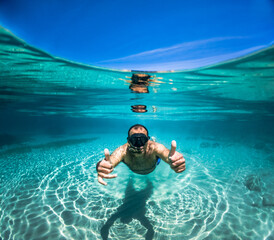 Young man snorkeling in crystal clear tropical sea