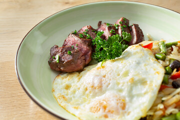 A view of a plate of steak and eggs.