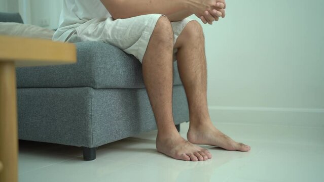 Man has a mental problem and shaking his legs while sitting on sofa.