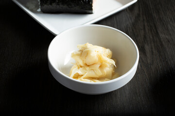 A closeup view of a condiment cup of sliced white ginger.