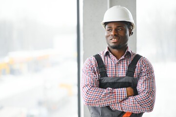 Smiling construction worker with arms crossed at site
