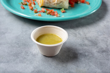 A view of a recycled paper condiment cup of salsa verde.