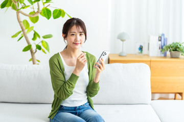 部屋でスマホを操作する若い女性