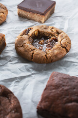 A view of a caramel peanut cookie, among other cookies and brownies.