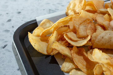 A closeup view of a pile of homemade potato chips on a tray.