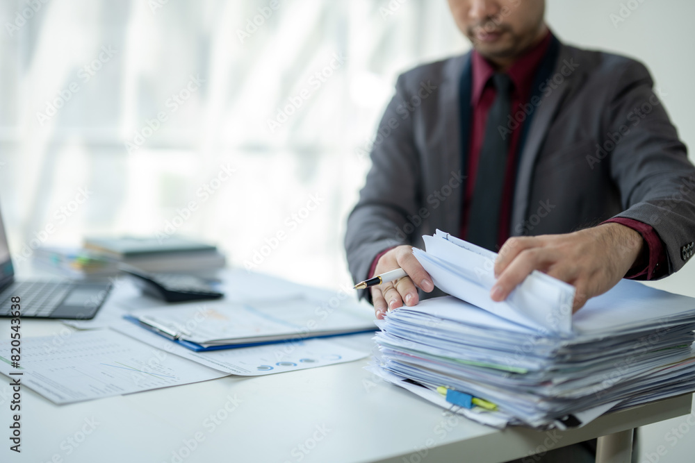 Wall mural a man is sitting at a desk with a pile of papers in front of him