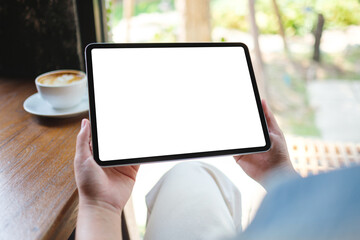 Mockup image of a woman holding digital tablet with blank white desktop screen in cafe