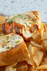 A closeup view of a meatball sandwich on a  tray of potato chips.