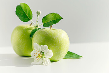 Close-up of two green apples with leaf and flower on light background. Tasty fruit concept.
