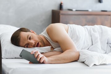 Sleepy bachelor on the bed ready to wake up or go to sleep. Study hard or burned out concept.