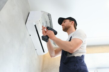 Happy Male Technician Repairing Air Conditioner.