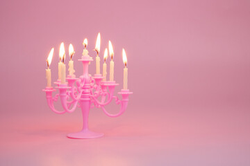 Pink candelabra with burning candles on pink background. Copy space for text.	