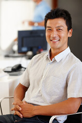 Portrait, man and happy in creative office, web designer sitting in chair in workplace. Smile, professional and Asian male person in business, confident and comfortable relaxing Japanese staff