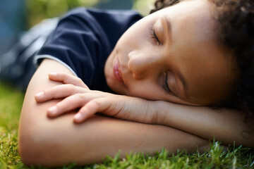 Boy, kid and sleeping on grass in garden of home for resting, exhausted and tired with dreaming in nature. Child, fatigue and nap on lawn in backyard with comfort, peace or relax for wellness outdoor