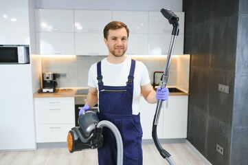 Happy Male Janitor Cleaning Carpet With Vacuum Cleaner