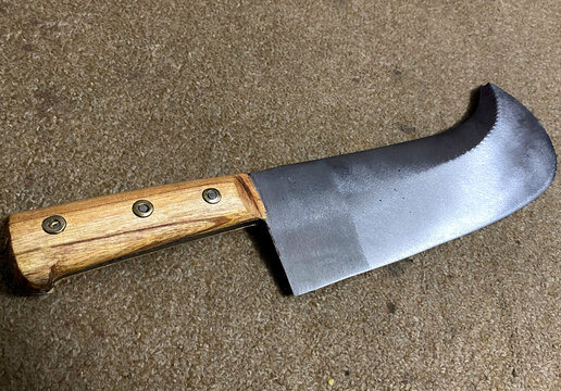 a bone chopping knife laying on the ground with a wooden handle