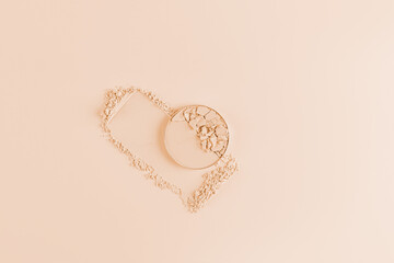 A round block of compact powder in a natural tone for facial skin care and beauty on a swatch of the powder. Beige background. Product presentation.