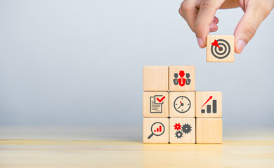 Businessman hand holding a Target icon on wooden cubes with business strategy icons. copy space