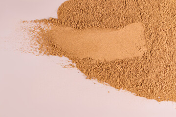 swatch of cosmetic structure powder powder in bronze tone. Top view. Beige background. Layout. Sample. Template. A copy space.