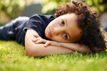 Portrait, summer and boy on grass, play and nature with fun, weekend break and boring. Face,...