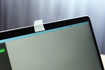 Close-up of a covering the webcam on a laptop with a piece of paper.