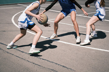 Teenage girls play street basketball on a street court in the city.