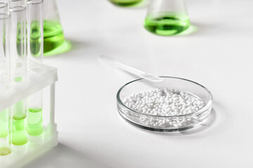 A Petri dish for chemical experiments with white granules against the background of other laboratory glassware.