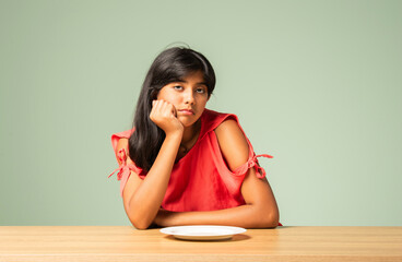 Indian asian small girl child saying no thanks to empty food plate