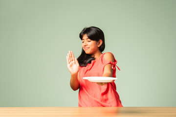 Indian asian small girl child saying no thanks to empty food plate