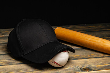 Baseball cap, ball and bat on wooden background
