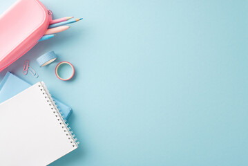 A neatly organized display of school supplies on a light blue background, featuring notebooks, pencils, and tapes for an inspiring educational setup