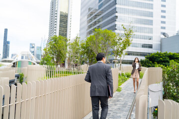 Confidence Asian businessman and businesswoman holding briefcase and digital tablet walking city...