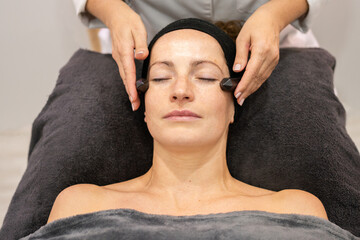 Beauty therapist massaging face of client with natural crystals