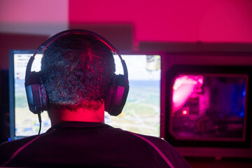 A gamer intensely focused on the screen, wearing headphones and immersed in the game.