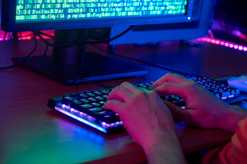 Close-up of a gamer’s hands typing rapidly on a backlit keyboard during gameplay