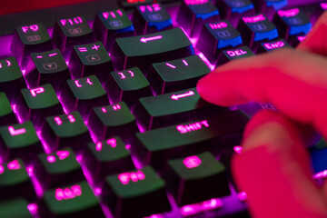 A close up photo for a gamer pressing the Enter key on a mechanical keyboard with RGB lights during gameplay