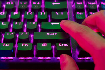 A close up photo for a gamer pressing the Enter key on a mechanical keyboard with RGB lights during gameplay
