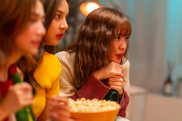 Group of Young Asian woman friends watching movie on television together in living room at home at...