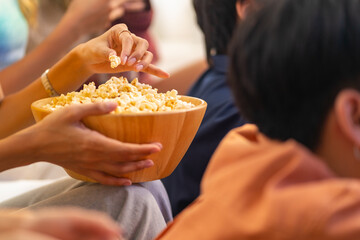 Group of Young Asian man and woman friends watching movie on television together in living room at...